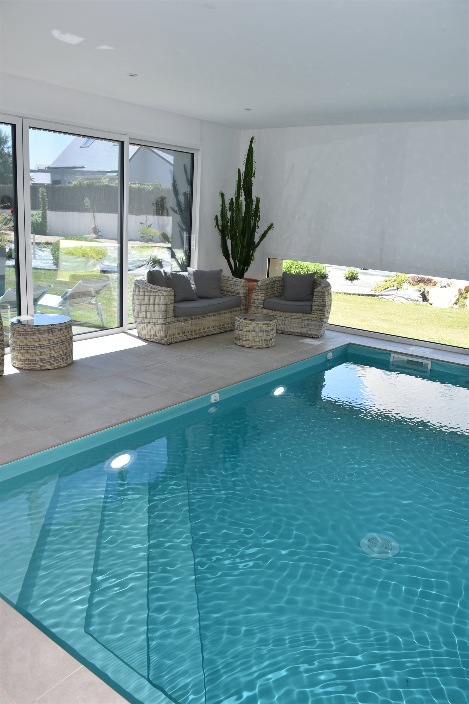 Salon détente au bord de la piscine intérieure, avec vue sur le jardin